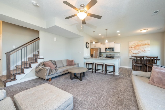 living room featuring ceiling fan, a textured ceiling, and carpet flooring