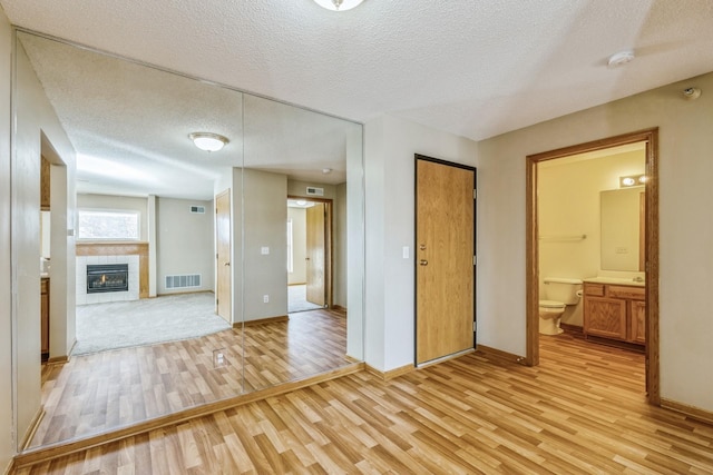 interior space with a textured ceiling, light hardwood / wood-style floors, and a tile fireplace