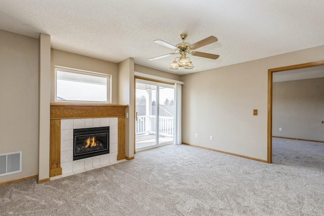 unfurnished living room featuring a textured ceiling, ceiling fan, light colored carpet, and a tile fireplace