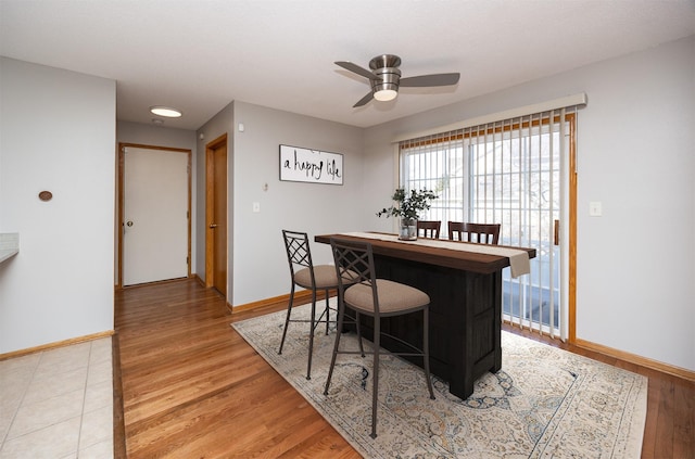 dining space featuring baseboards, light wood-style floors, and ceiling fan