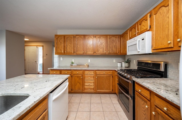 kitchen featuring light tile patterned floors, white appliances, tasteful backsplash, and brown cabinets