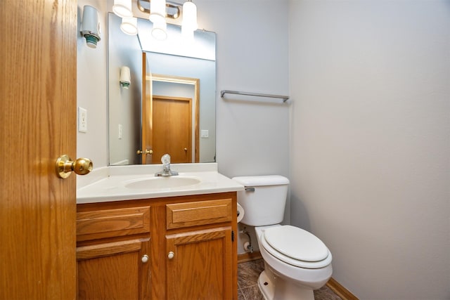 half bathroom with toilet, vanity, and baseboards