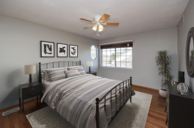 bedroom featuring visible vents, ceiling fan, baseboards, and wood finished floors