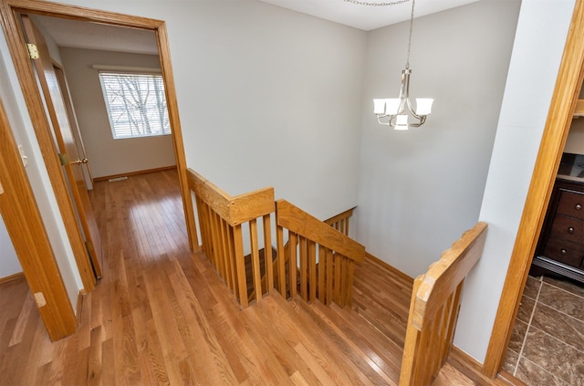 staircase featuring a chandelier, baseboards, and wood finished floors