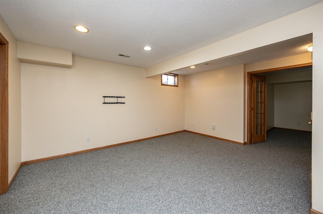 basement featuring carpet, visible vents, baseboards, recessed lighting, and a textured ceiling