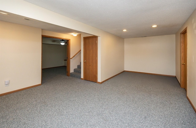 finished below grade area featuring stairway, carpet, baseboards, and a textured ceiling