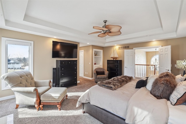 carpeted bedroom with ceiling fan and a tray ceiling