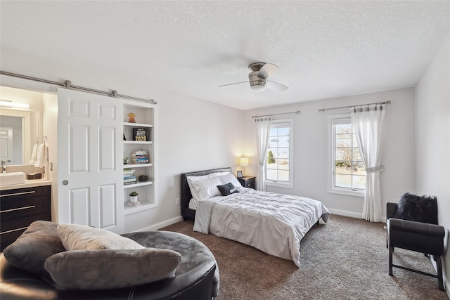 bedroom with carpet floors, ceiling fan, a barn door, a textured ceiling, and a sink