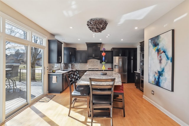 kitchen with a breakfast bar area, light hardwood / wood-style floors, stainless steel appliances, and a kitchen island