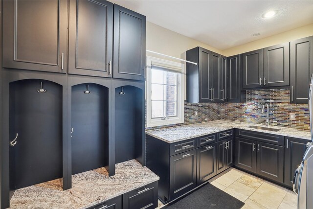 kitchen featuring light stone countertops, range, tasteful backsplash, and sink