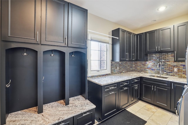 kitchen with decorative backsplash, range, light stone countertops, a sink, and recessed lighting