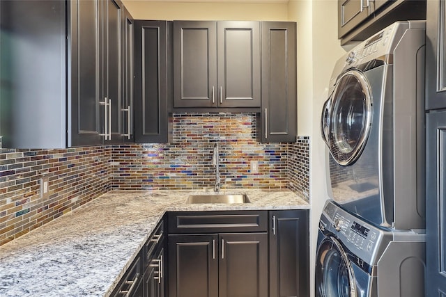 clothes washing area with a sink, cabinet space, and stacked washer / drying machine