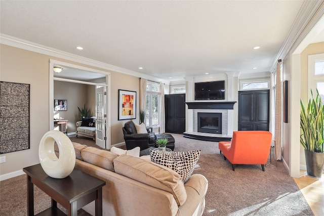 carpeted living room featuring crown molding, recessed lighting, baseboards, and a glass covered fireplace