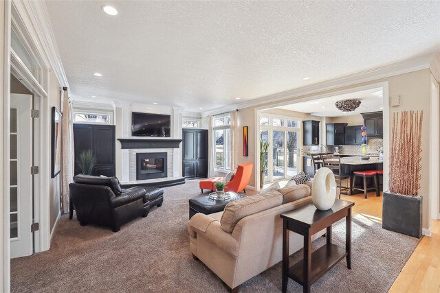 living room with a brick fireplace, hardwood / wood-style floors, crown molding, and a textured ceiling