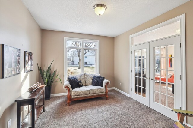 sitting room featuring a textured ceiling, french doors, and carpet flooring