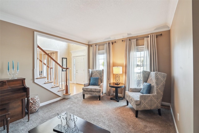 sitting room with carpet floors, ornamental molding, baseboards, and stairway