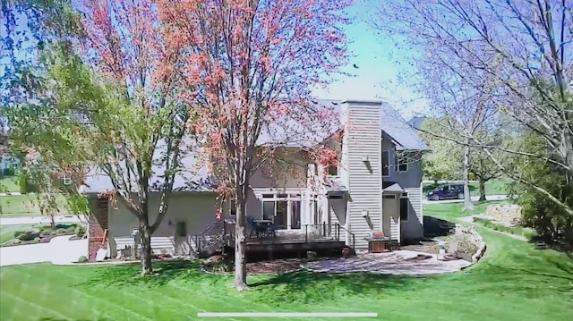 rear view of property featuring a yard, a deck, and a chimney