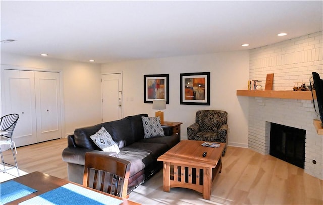 living room with a brick fireplace and light wood-type flooring