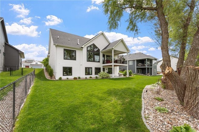 back of house featuring a lawn and a balcony