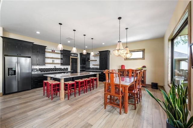 dining room with light wood-type flooring, sink, and a chandelier