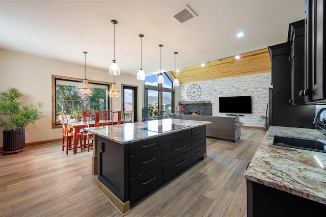 kitchen featuring hanging light fixtures, a fireplace, sink, and a center island