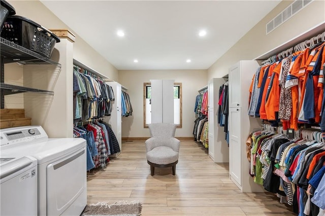 walk in closet with light hardwood / wood-style flooring and washing machine and clothes dryer