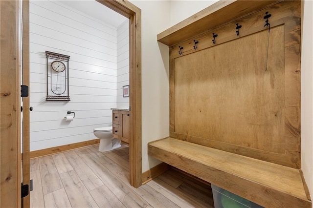 mudroom featuring light wood-type flooring and wood walls