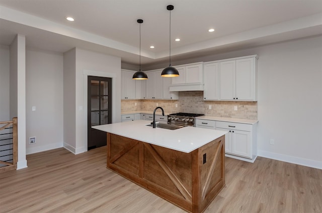 kitchen with white cabinetry, a center island with sink, decorative light fixtures, and sink