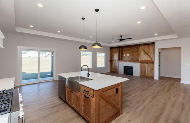 kitchen with pendant lighting, dishwasher, a raised ceiling, and an island with sink