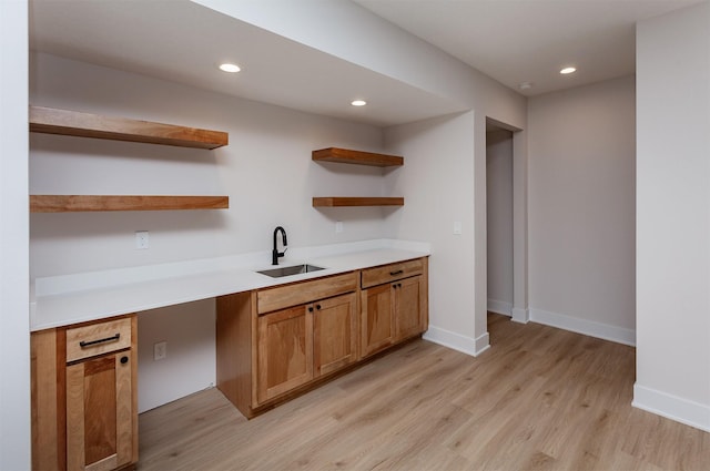 kitchen featuring built in desk, light hardwood / wood-style flooring, and sink