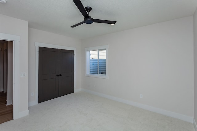 unfurnished bedroom with ceiling fan, a closet, light carpet, and a textured ceiling