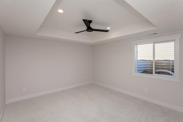 carpeted spare room featuring a raised ceiling and ceiling fan