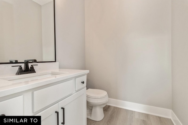 bathroom with toilet, hardwood / wood-style flooring, and vanity