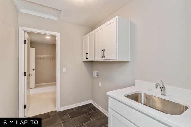 clothes washing area with sink, washer hookup, a textured ceiling, and cabinets