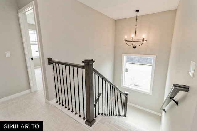 stairway with carpet floors and an inviting chandelier