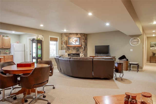 carpeted living room featuring a stone fireplace