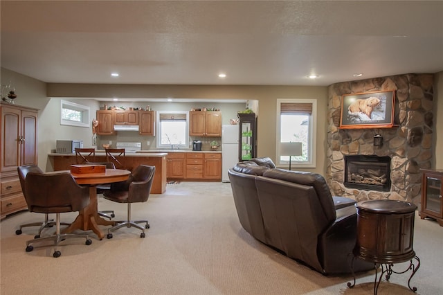 carpeted living room featuring plenty of natural light, sink, and a fireplace