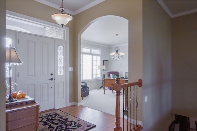 foyer entrance with light hardwood / wood-style flooring, crown molding, and a chandelier