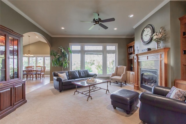 living room featuring a premium fireplace, light colored carpet, vaulted ceiling, ornamental molding, and ceiling fan with notable chandelier