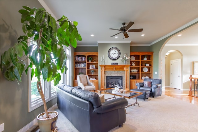 carpeted living room featuring ceiling fan, a tile fireplace, and ornamental molding