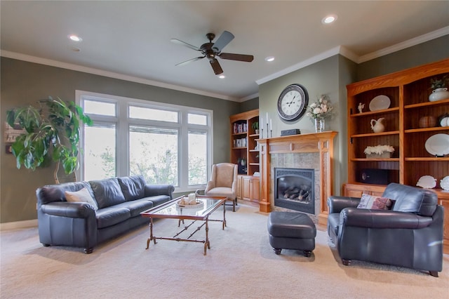 living room featuring ceiling fan, light colored carpet, a tiled fireplace, and crown molding