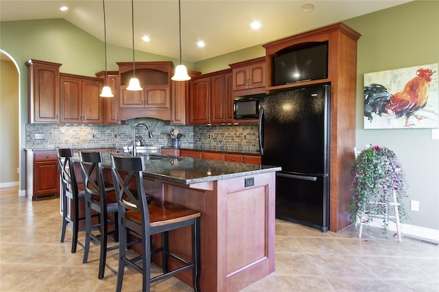 kitchen featuring a center island with sink, backsplash, dark stone countertops, vaulted ceiling, and black appliances