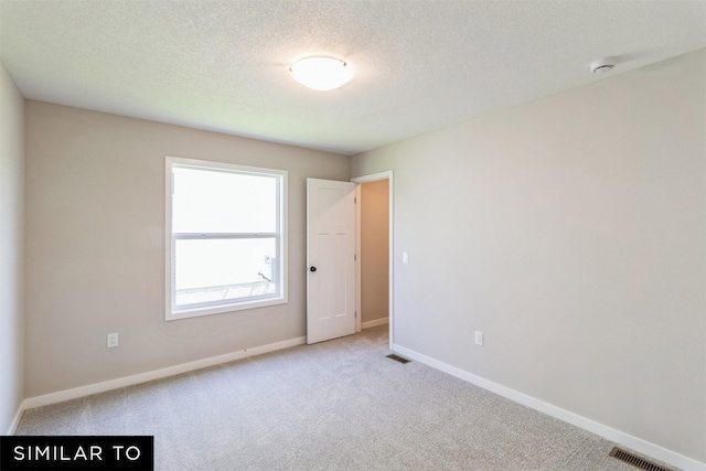 carpeted spare room featuring a textured ceiling