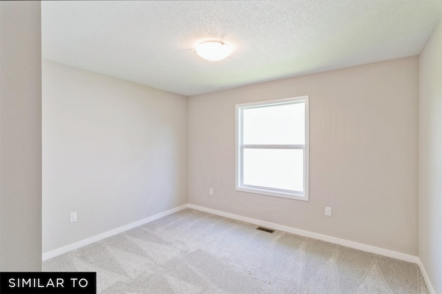 carpeted empty room featuring a textured ceiling