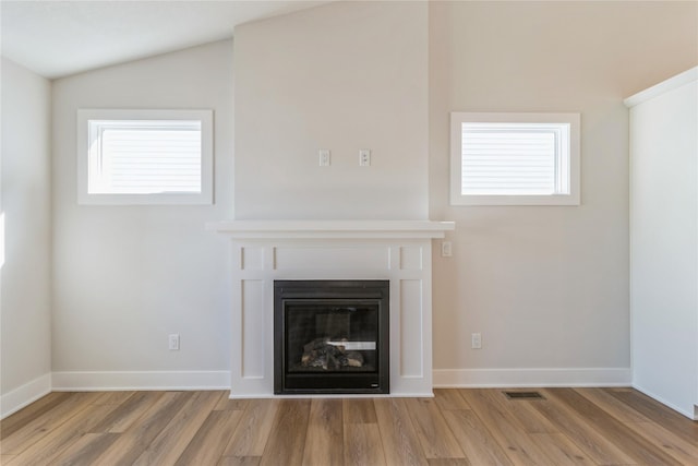 4207 NE 3rd St, Ankeny, IA 50021 - unfurnished living room featuring a wealth of natural light, a glass covered fireplace, wood finished floors, and visible vents