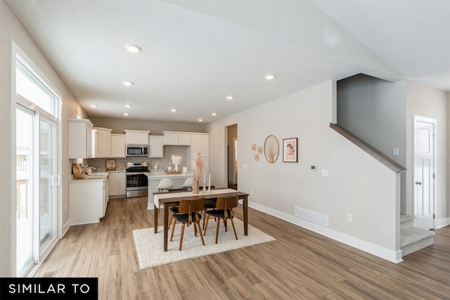 dining area with vaulted ceiling, light hardwood / wood-style flooring, and sink