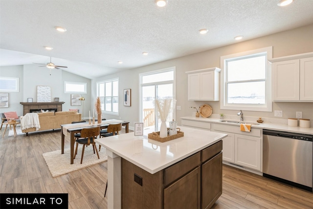 kitchen featuring dishwasher, white cabinets, vaulted ceiling, light hardwood / wood-style flooring, and sink