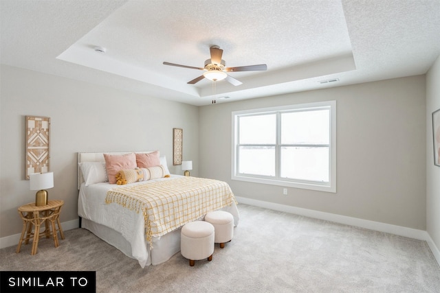 carpeted bedroom featuring a raised ceiling, ceiling fan, and a textured ceiling