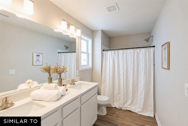 bathroom with toilet, vanity, wood-type flooring, and walk in shower