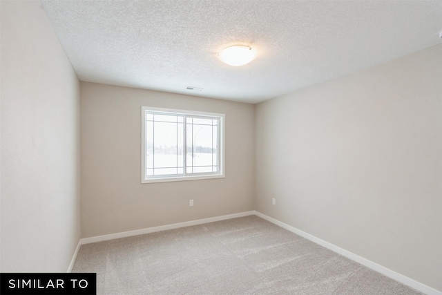 carpeted empty room with a textured ceiling